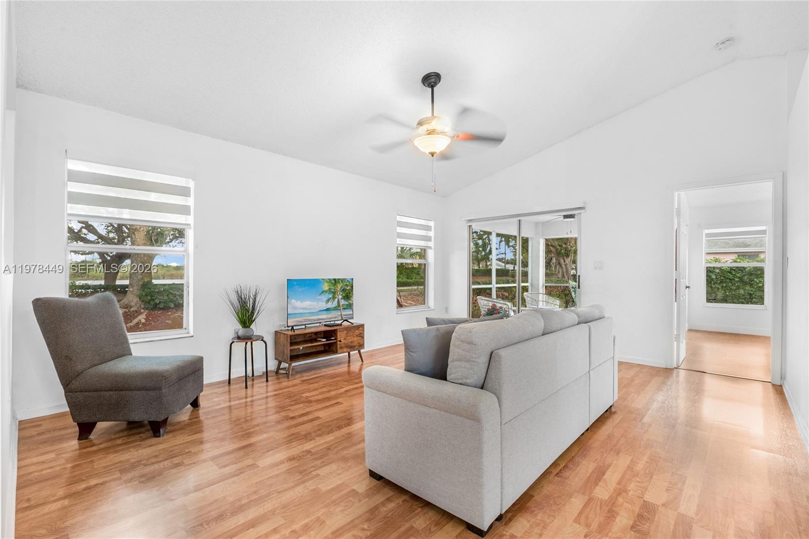 A living room features white walls, wood-look flooring, a ceiling fan, and a gray sofa — 2020 SE 5th Pl, Homestead FL 33033, HOMESTEAD, FL