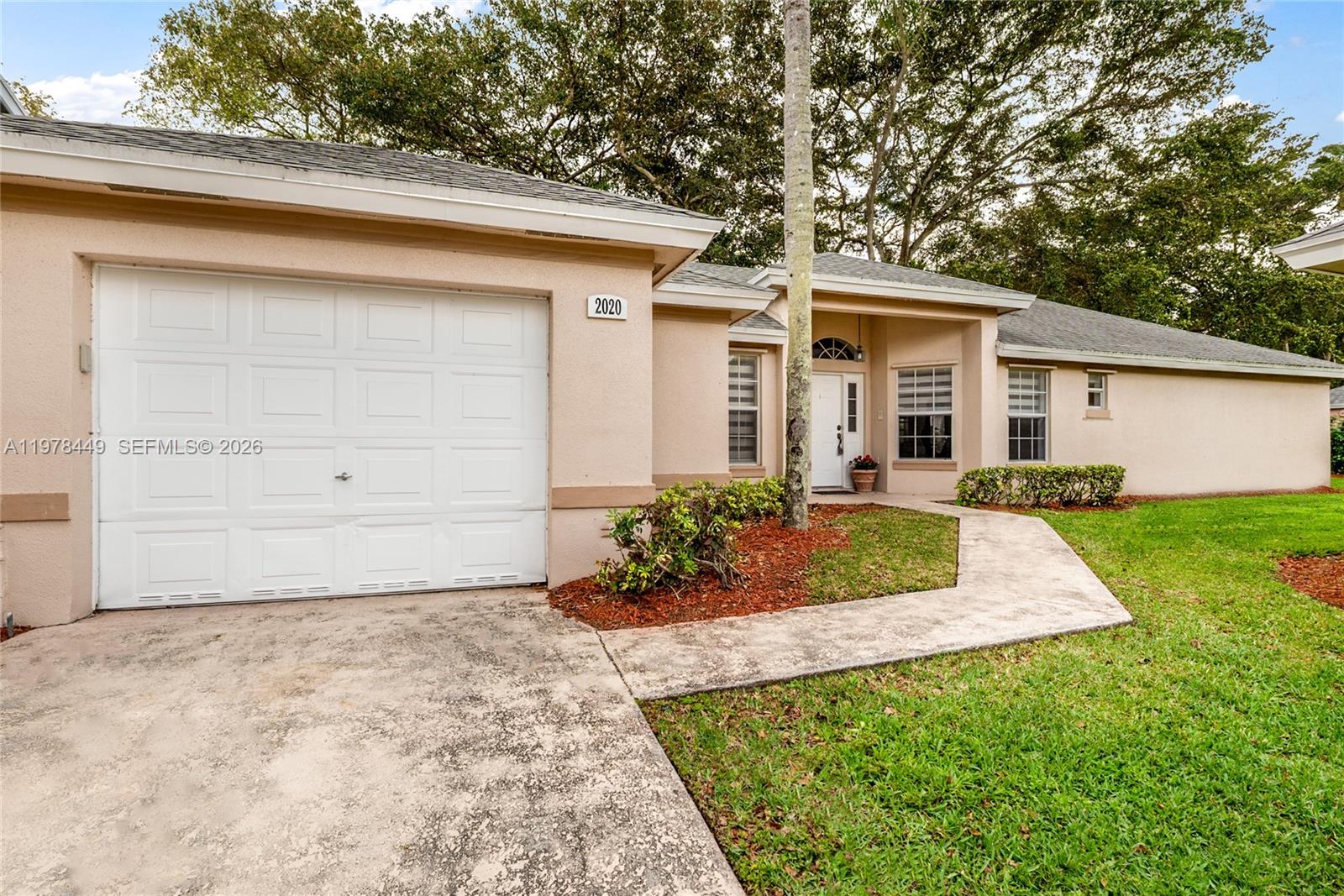 A single-story house with a beige exterior, a one-car garage, and a concrete walkway — 2020 SE 5th Pl, Homestead FL 33033, HOMESTEAD, FL