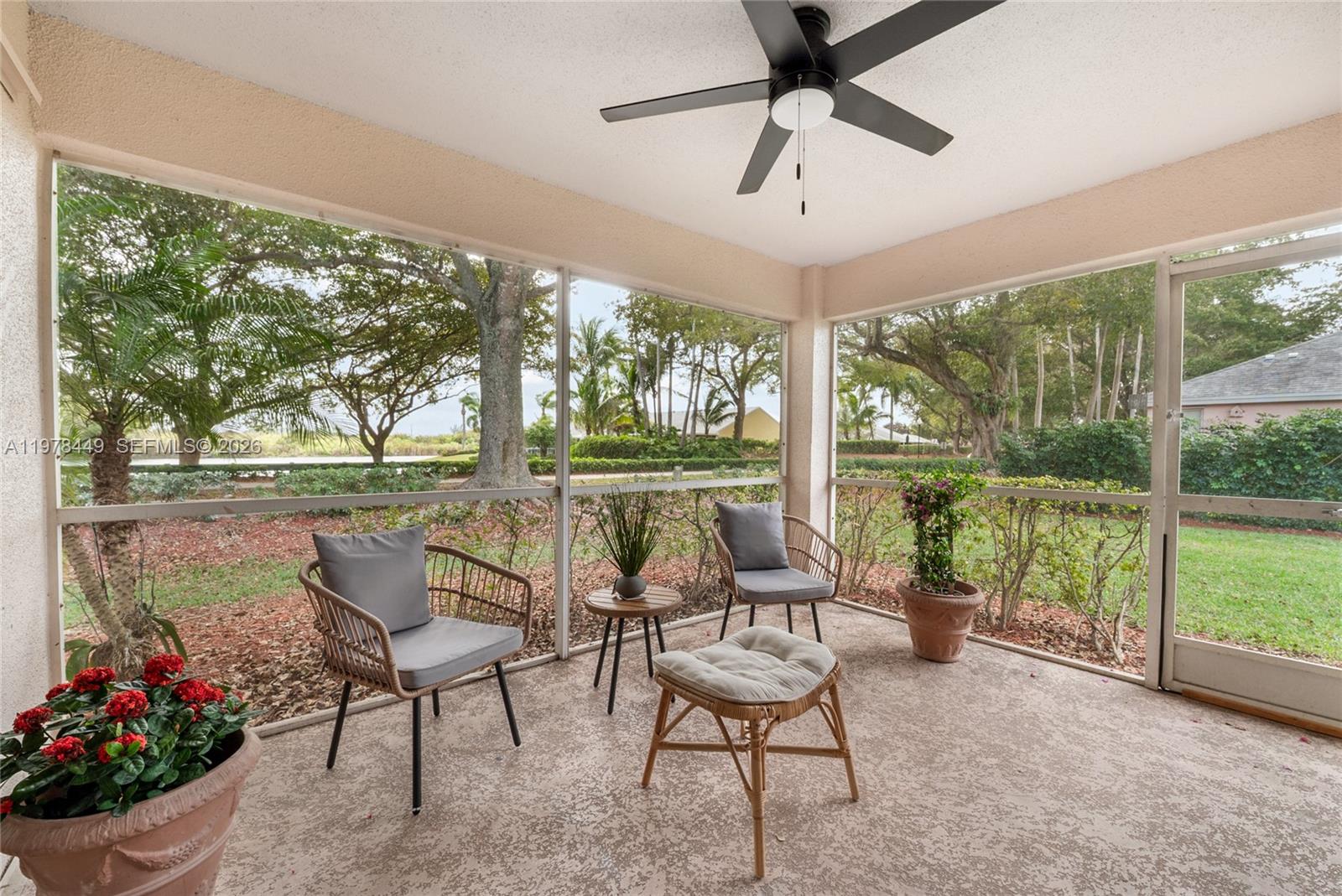 A screened-in patio features two chairs, a small table, an ottoman, and a ceiling fan — 2020 SE 5th Pl, Homestead FL 33033, HOMESTEAD, FL