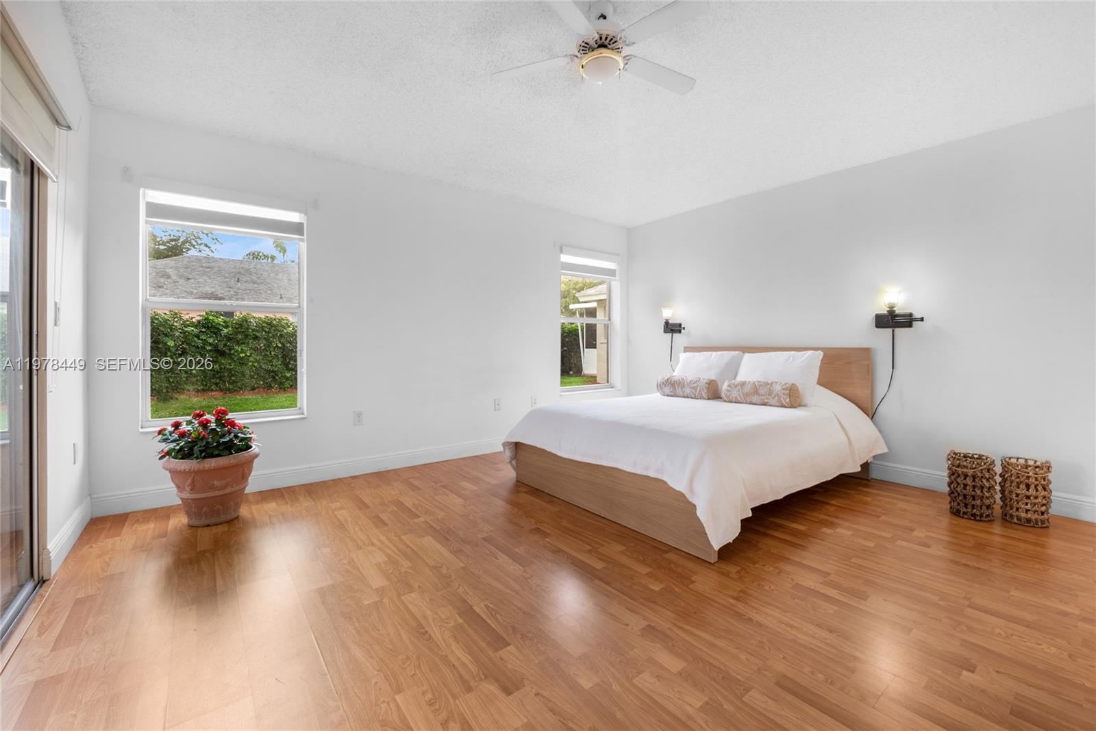 A bedroom features light wood flooring, white walls, a ceiling fan, and a platform bed — 2020 SE 5th Pl, Homestead FL 33033, HOMESTEAD, FL
