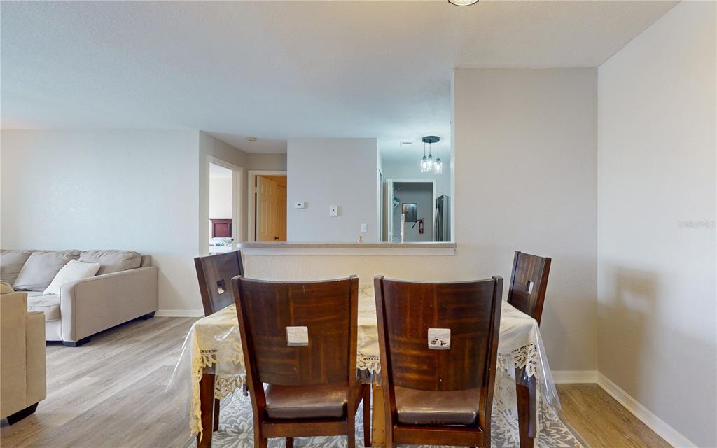 A dining area with a wooden table and chairs sits before an open kitchen counter — 8801 LATREC AVENUE UNIT 8208, ORLANDO, FL