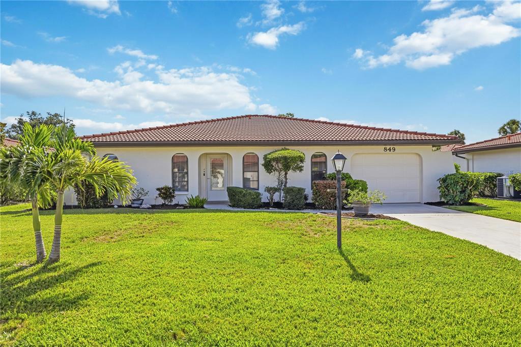 A single-story house with a white stucco exterior, a tiled roof, and a front lawn — 849 SENDA PLATA UNIT 15, VENICE, FL