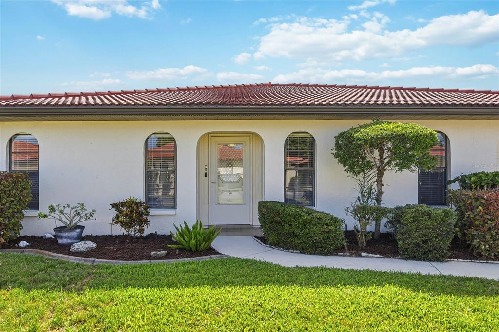 The exterior of a single-story house features a white stucco facade, arched windows, and a tiled roof — 849 SENDA PLATA UNIT 15, VENICE, FL