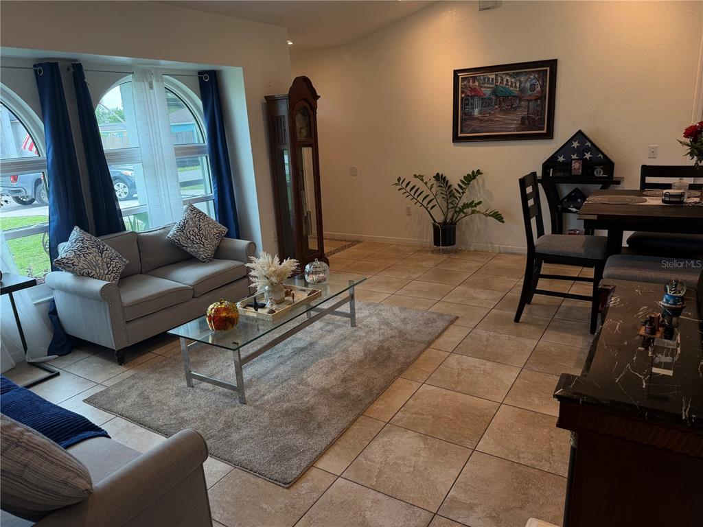 A living and dining area features tile floors, a glass coffee table, and arched windows — 3824 HOLIN LANE, NORTH PORT, FL