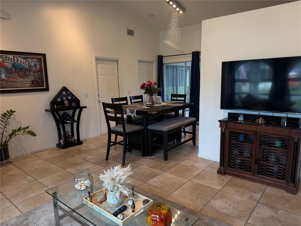 A dining area with a dark wood table and chairs sits adjacent to a living room — 3824 HOLIN LANE, NORTH PORT, FL