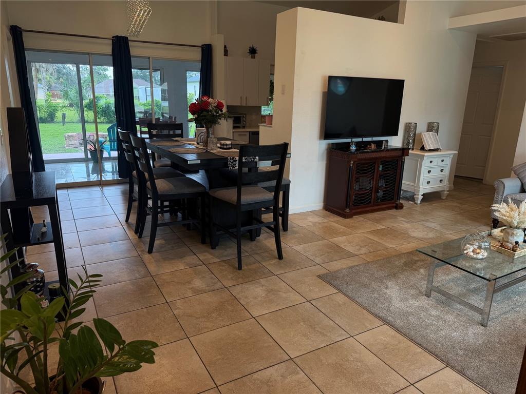 An open-concept dining and living area features tile flooring, a dark wood dining set, and a television — 3824 HOLIN LANE, NORTH PORT, FL