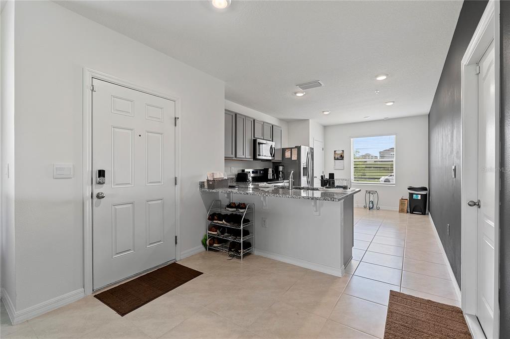 An entryway leads into a kitchen with gray cabinets, granite countertops, and tile flooring — 3476 MAJOR OAK BOULEVARD, APOPKA, FL