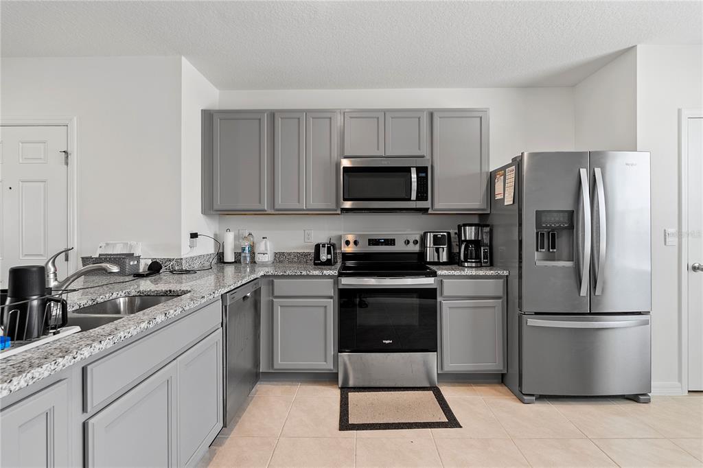A kitchen features gray cabinets, stainless steel appliances, and granite countertops — 3476 MAJOR OAK BOULEVARD, APOPKA, FL