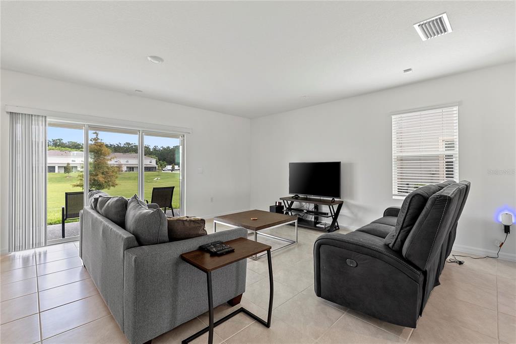 A living room features gray sofas, a coffee table, a television, and sliding glass doors — 3476 MAJOR OAK BOULEVARD, APOPKA, FL