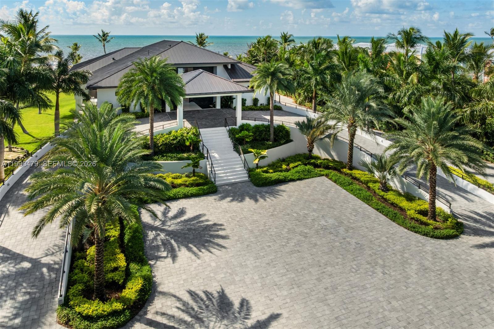 An aerial view shows a modern house with a paved driveway, palm trees, and ocean — 87429 Old Hwy, Islamorada FL 33036, ISLAMORADA, FL