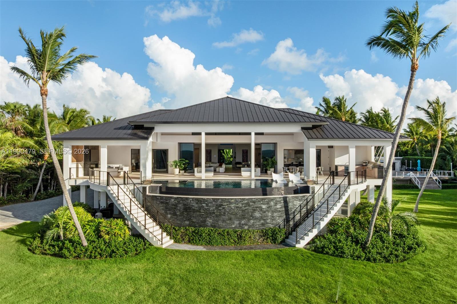 An elevated house with a dark metal roof, a curved infinity pool, and dual staircases — 87429 Old Hwy, Islamorada FL 33036, ISLAMORADA, FL