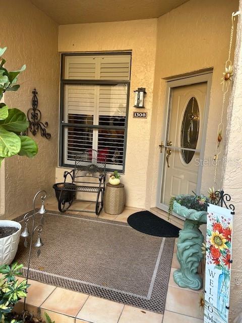 A covered entryway features a front door, a window with shutters, and a metal chair — 1308 LAKE WILLISARA CIRCLE UNIT 28-12, ORLANDO, FL