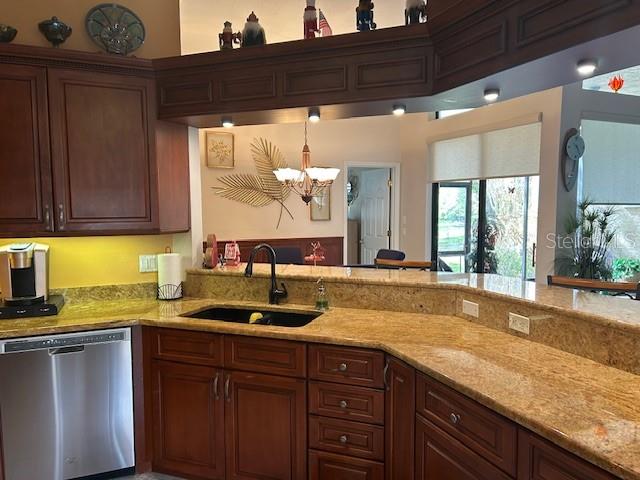 A kitchen features dark wood cabinets, granite countertops, a stainless steel dishwasher, and a sink — 1308 LAKE WILLISARA CIRCLE UNIT 28-12, ORLANDO, FL