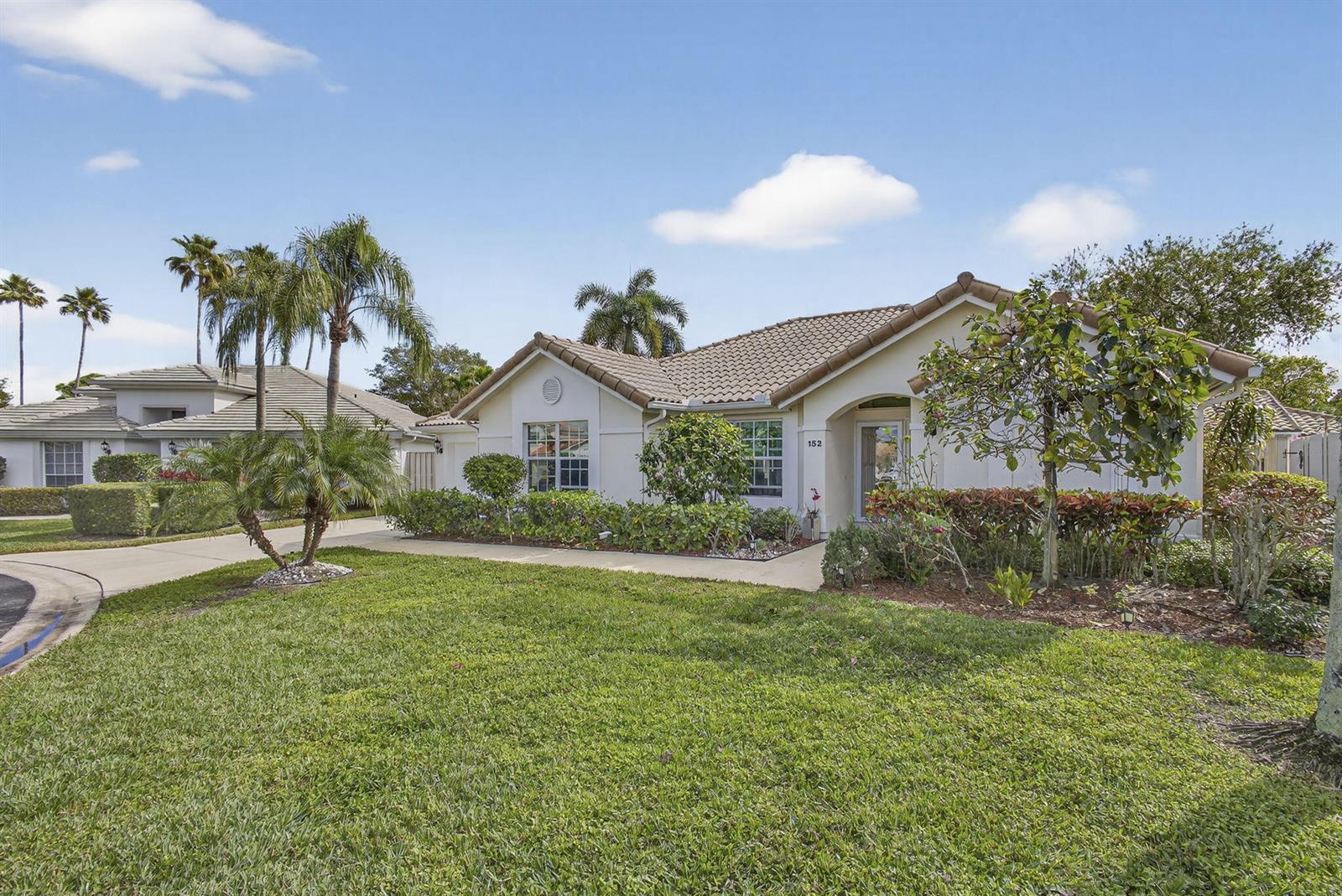 A single-story house with a tiled roof, beige stucco exterior, and landscaped front yard — 152 Eagleton Court, Palm Beach Gardens FL 33418, PALM BEACH GARDENS, FL