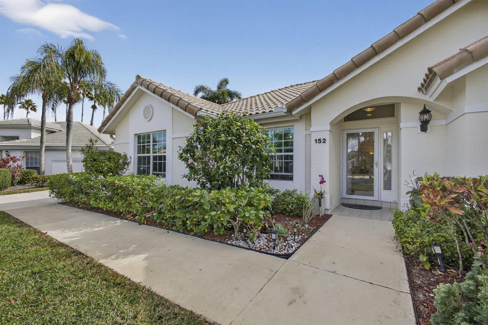 A single-story house with a beige stucco exterior, tile roof, and a landscaped front walkway — 152 Eagleton Court, Palm Beach Gardens FL 33418, PALM BEACH GARDENS, FL