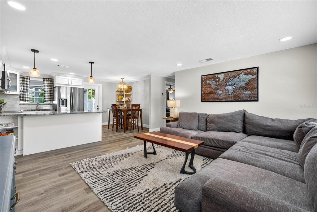 A living room with a grey sectional sofa, coffee table, and an open kitchen area — 6827 80TH TERRACE N, PINELLAS PARK, FL