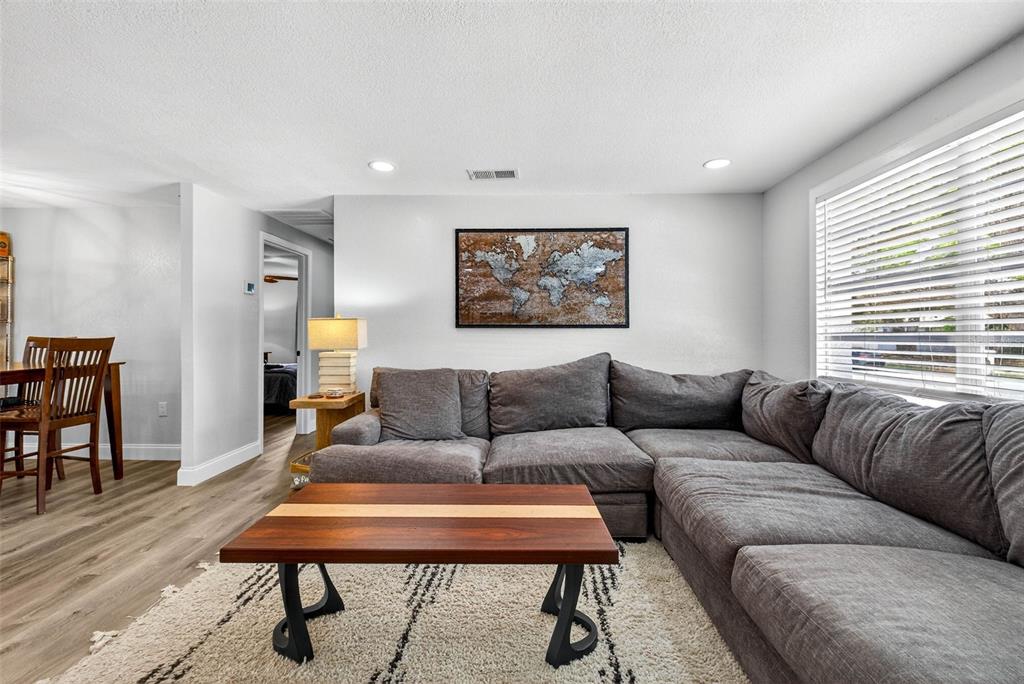 A living room features a grey sectional sofa, a wooden coffee table, and a world map — 6827 80TH TERRACE N, PINELLAS PARK, FL