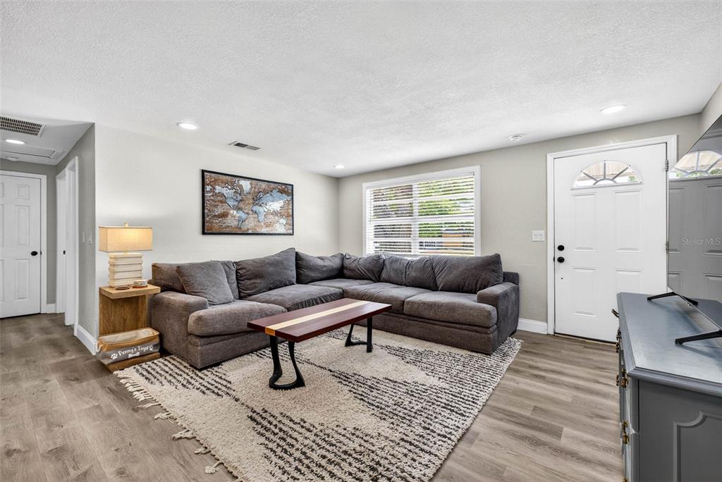 A living room features a grey sectional sofa, a wooden coffee table, and a patterned rug — 6827 80TH TERRACE N, PINELLAS PARK, FL