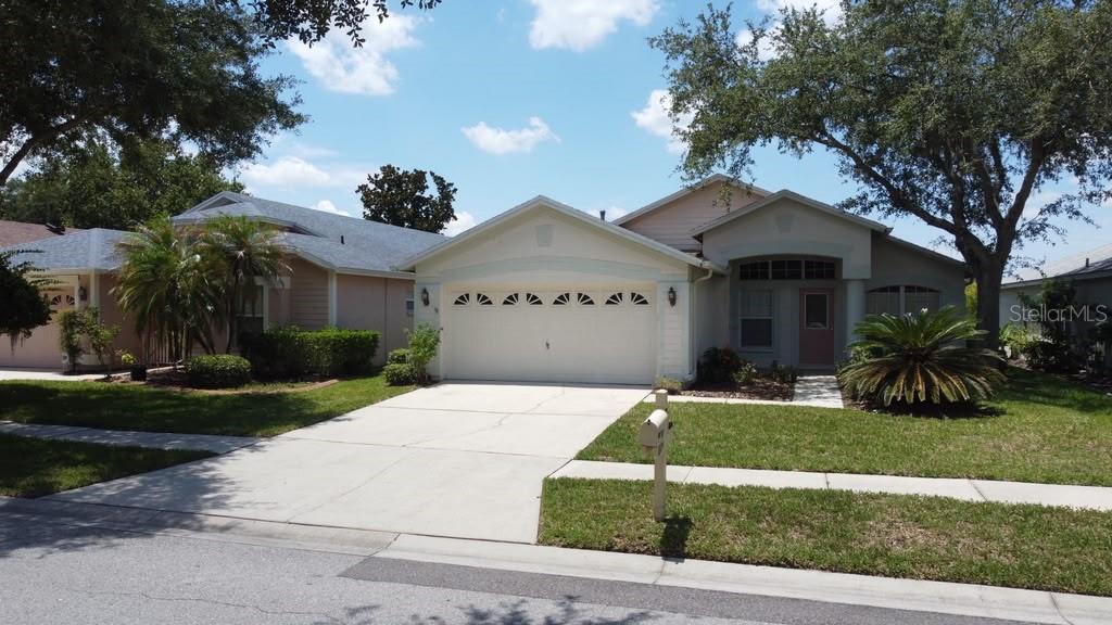A single-story suburban house with a two-car garage, light-colored siding, and a front lawn — 18014 ARBOR CREST DRIVE, TAMPA, FL