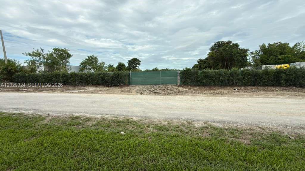 A gravel road leads to a fenced lot bordered by a dense hedge and trees — SW 213TH AVE, Miami FL 33187, MIAMI, FL