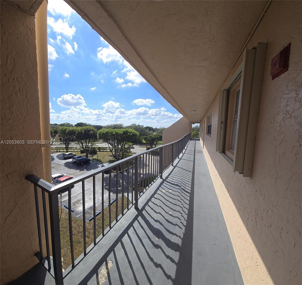 An outdoor walkway with a metal railing overlooks a parking lot and trees — 13707 Kendale Lakes Cir, Miami FL 33183, MIAMI, FL