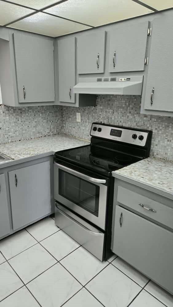A kitchen features gray cabinets, a mosaic tile backsplash, speckled countertops, and a stainless stove — 13707 Kendale Lakes Cir, Miami FL 33183, MIAMI, FL