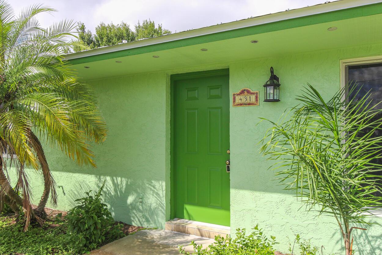 A bright green exterior wall features a matching green front door and a house number plaque — 431 NE Julia Court, Jensen Beach FL 34957, JENSEN BEACH, FL