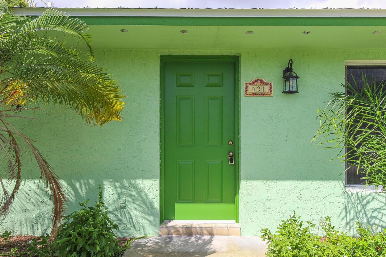 A green front door with a house number plaque and a wall-mounted lantern light — 431 NE Julia Court, Jensen Beach FL 34957, JENSEN BEACH, FL