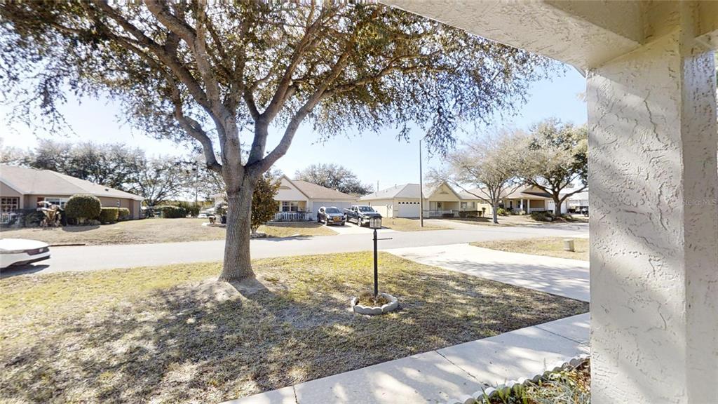 A view from a porch looking out at a suburban street with houses and trees — 9771 SW 97TH LANE, OCALA, FL