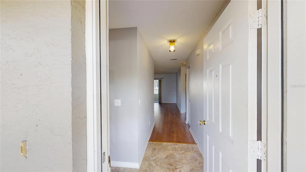 An entryway leads into a hallway with tile flooring transitioning to wood-look laminate flooring — 9771 SW 97TH LANE, OCALA, FL