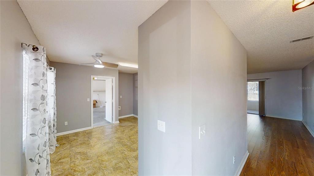 An interior view shows a tiled room with a ceiling fan and a wood-floored hallway — 9771 SW 97TH LANE, OCALA, FL