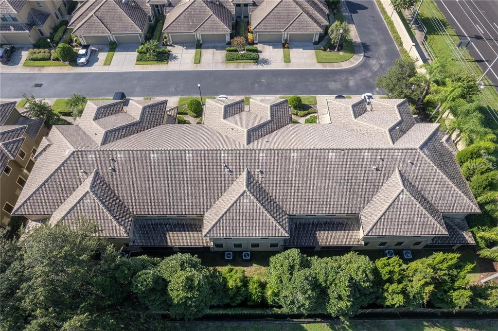 An aerial view shows the tiled roof of a multi-unit residential building with surrounding landscaping — 2527 SILVERBACK COURT, PALM HARBOR, FL
