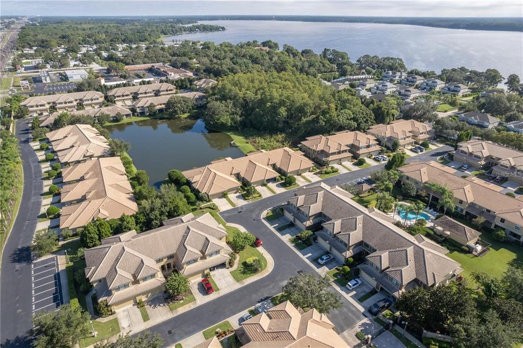 An aerial view shows a residential complex with townhouses, a pond, and a large lake — 2527 SILVERBACK COURT, PALM HARBOR, FL
