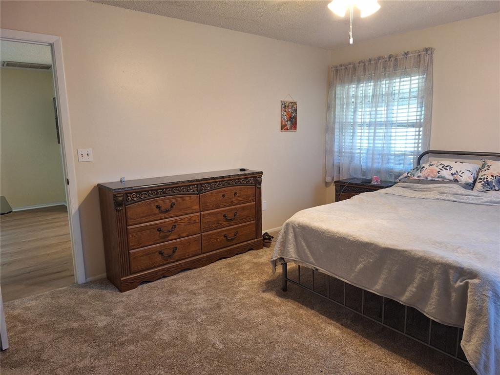 A bedroom with carpeted flooring, a wooden dresser, and a bed near a window — 419 FALCON AVENUE, EDGEWATER, FL