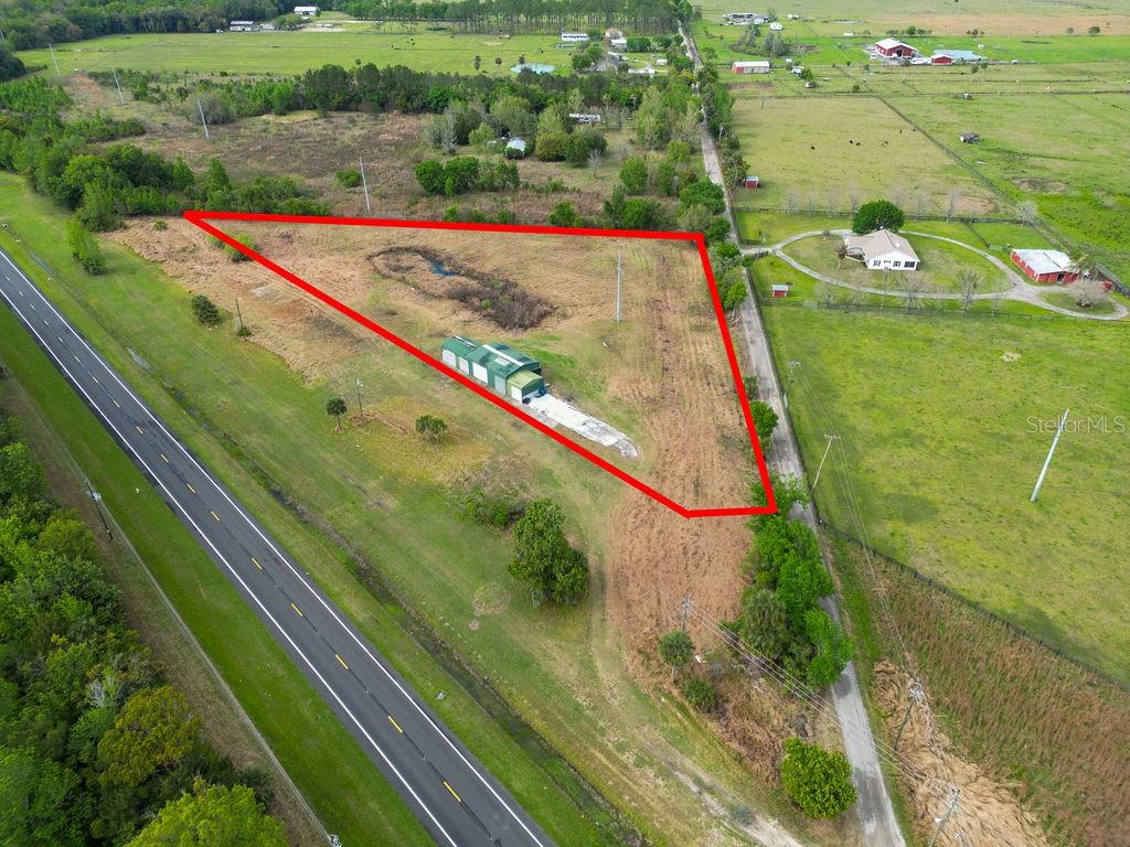 An aerial view shows a triangular plot of land with a small building and road — 6029 US HIGHWAY 17, DE LEON SPRINGS, FL