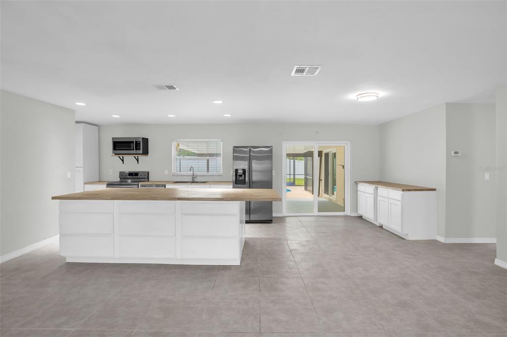 A kitchen with white cabinets, a large wooden island, stainless steel appliances, and tile flooring — 108 KILKENNY COURT, LONGWOOD, FL