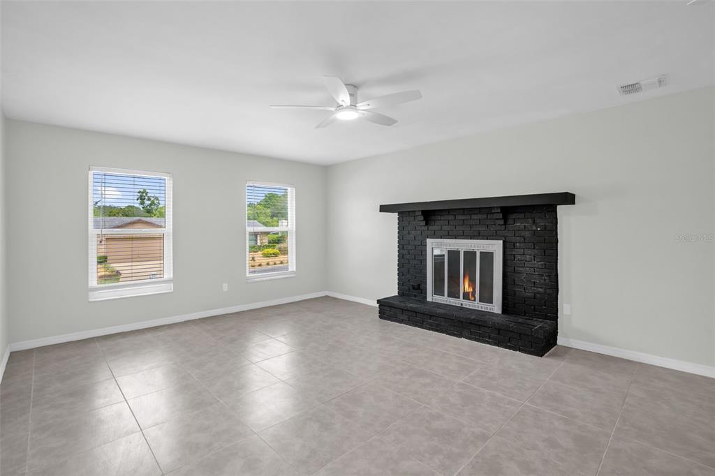 A living room features light gray tile flooring, white walls, and a black brick fireplace — 108 KILKENNY COURT, LONGWOOD, FL