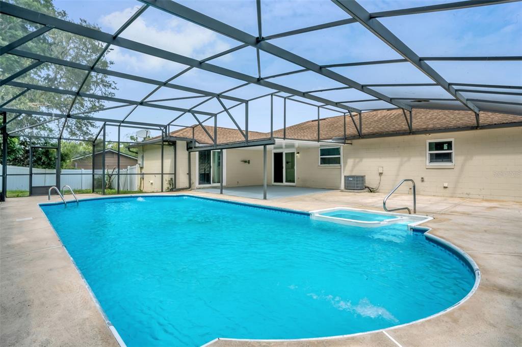 A screened-in swimming pool and attached spa sit on a concrete patio behind a house — 108 KILKENNY COURT, LONGWOOD, FL