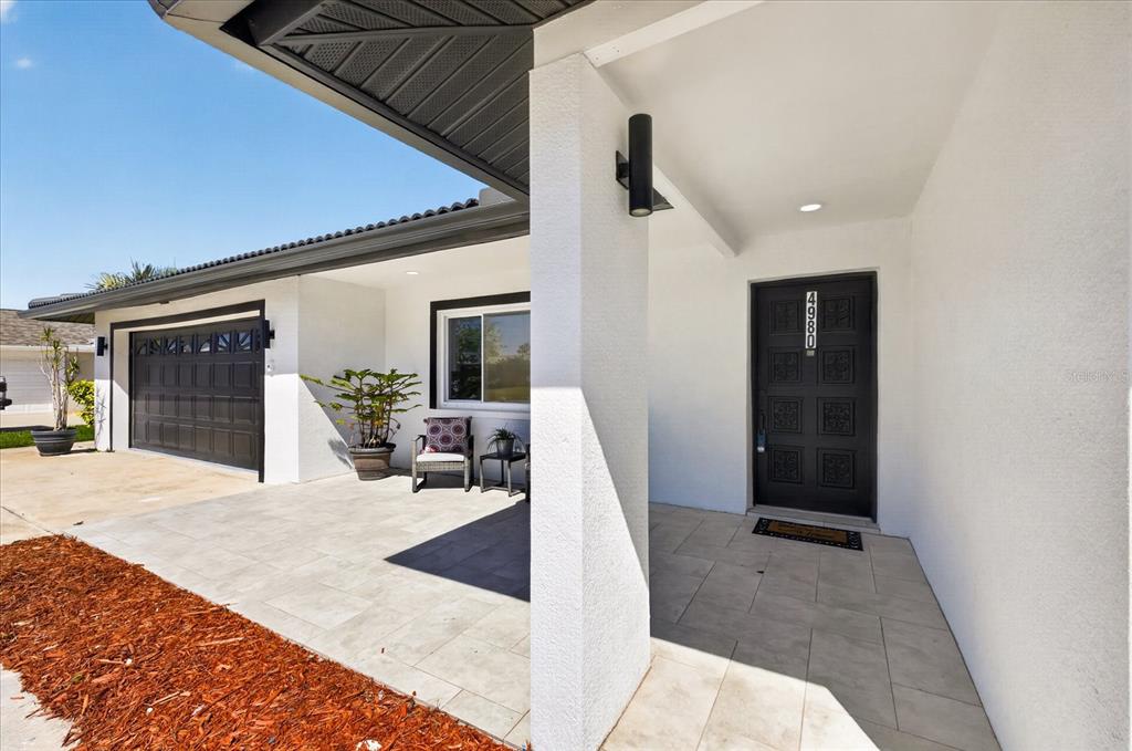 The exterior of a house features a black garage door, a front porch, and a door — 4980 GALLEON COURT, NEW PORT RICHEY, FL