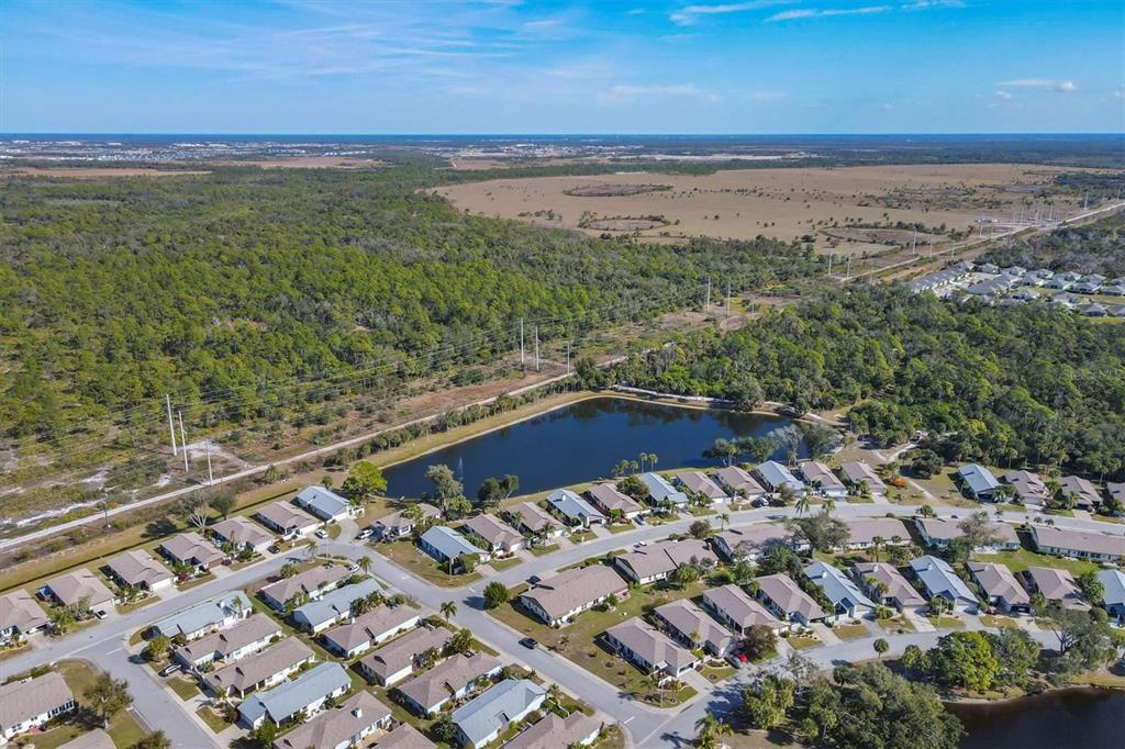 An aerial view shows a residential neighborhood with a central pond surrounded by suburban houses — 687 LINDEN DRIVE, ENGLEWOOD, FL