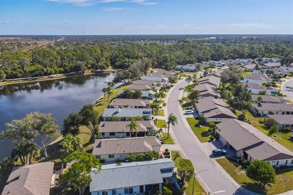 An aerial view shows a suburban neighborhood with houses along a lake and street — 687 LINDEN DRIVE, ENGLEWOOD, FL