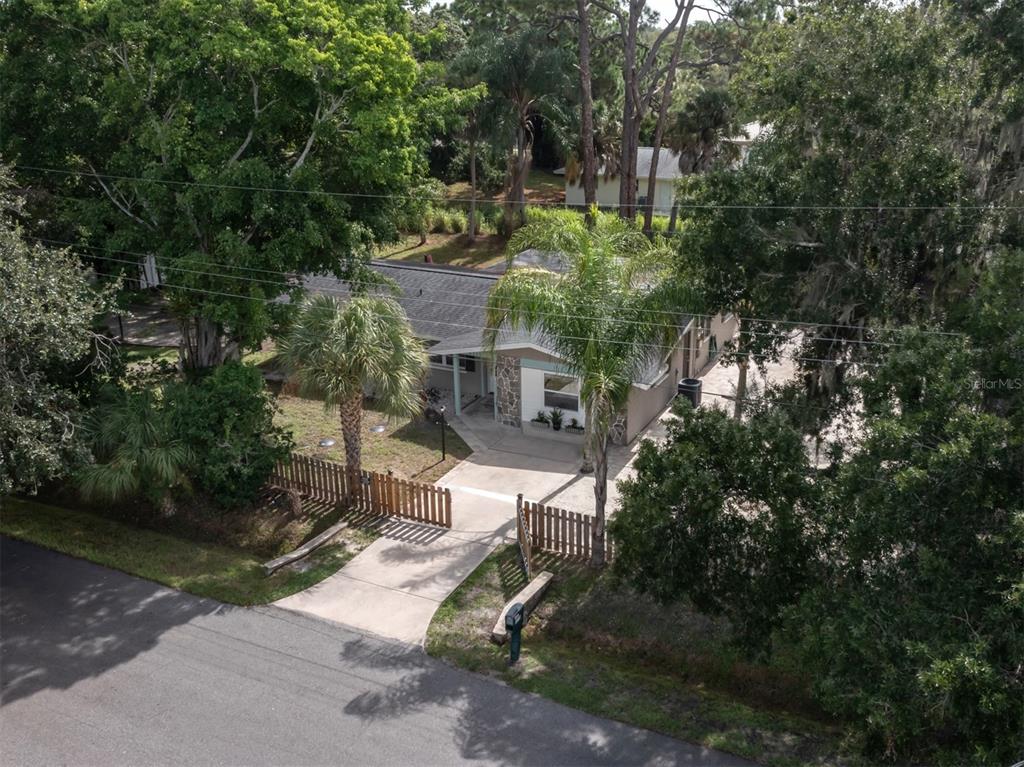 An aerial view shows a single-story house with a fenced front yard and concrete driveway — 6115 CARLTON AVENUE, SARASOTA, FL
