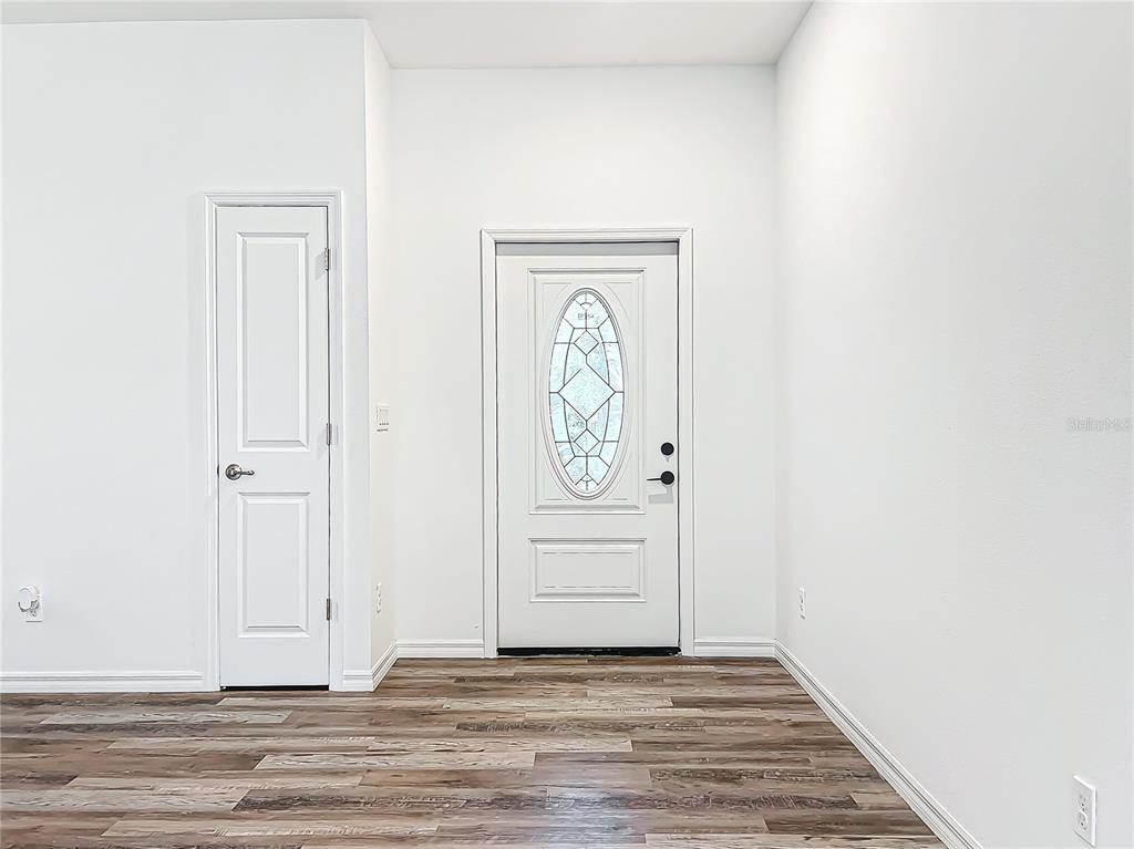 An entryway features white walls, wood-look flooring, a closet door, and a front door — 2391 YANKEE TERRACE, NORTH PORT, FL