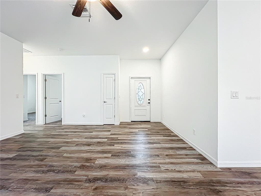 An interior view of an entryway with wood-look flooring, white walls, and three white doors — 2391 YANKEE TERRACE, NORTH PORT, FL
