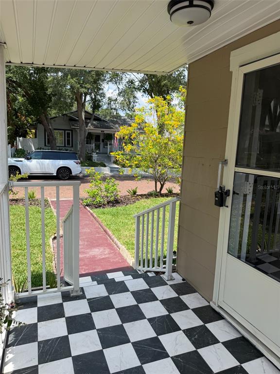 A covered porch features a black and white checkered floor and white railings — 124 20TH AVENUE N, ST PETERSBURG, FL