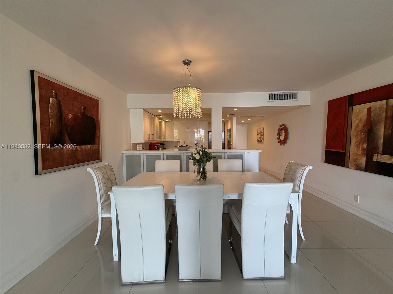 A dining room features a white table, six chairs, and a crystal chandelier — 3140 S Ocean Dr # 310, Hallandale Beach FL 33009, HALLANDALE BEACH, FL