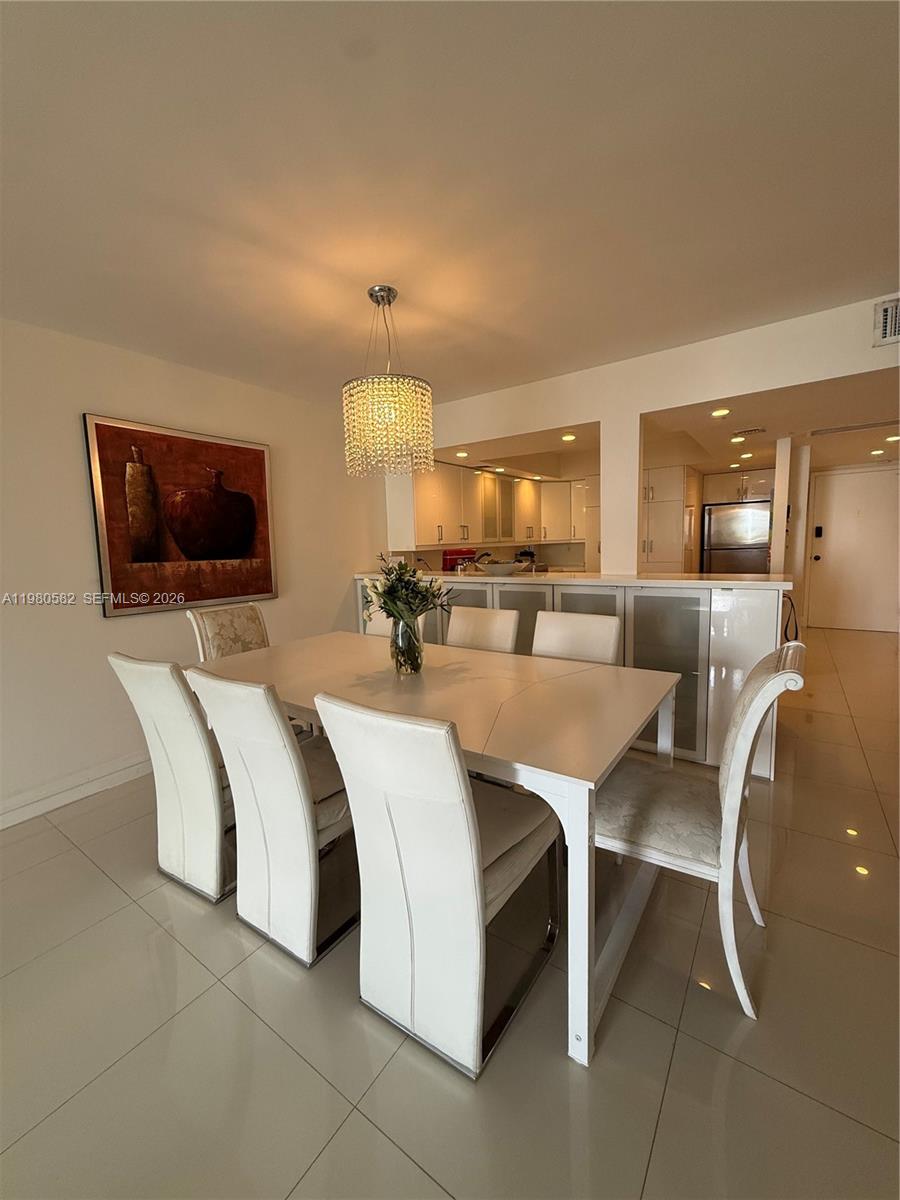 A dining area features a white table, six chairs, and a crystal chandelier — 3140 S Ocean Dr # 310, Hallandale Beach FL 33009, HALLANDALE BEACH, FL