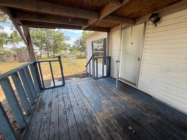 A weathered wooden deck with a railing leads to a white door on a house — 3903 MORGAN HORSE WAY, LAKE WALES, FL
