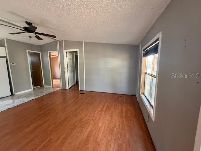 An interior view of a room with wood-look flooring, gray walls, and a ceiling fan — 3903 MORGAN HORSE WAY, LAKE WALES, FL