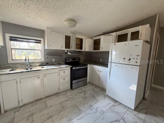 A kitchen with white cabinets, a stainless steel stove, a white refrigerator, and marble-patterned tile flooring — 3903 MORGAN HORSE WAY, LAKE WALES, FL
